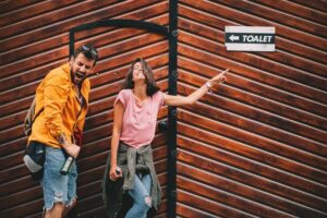 Young-couple-with-beer-in-hand-is-searching-for-a-public-toilet-on-the-street-cm