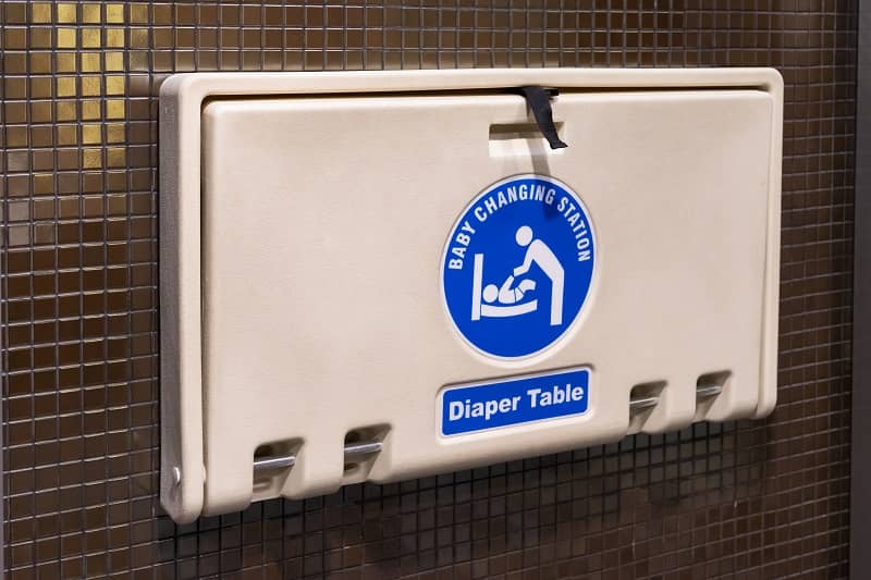 white plastic diaper table on brown ceramic wall in toilet. Baby diaper table in a public restroom-cm