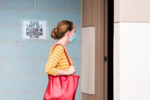 Woman wearing face mask waits to enter bathroom-cm