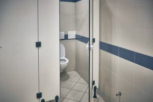 Open door of public toilet stall. Toilet bowl inside toilet stall-cm