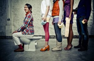 happy eccentric guy on the toilette while a line of people waits for their turn-cm