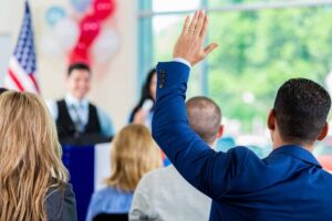 Hispanic man raising hand during political town hall meeting-cm